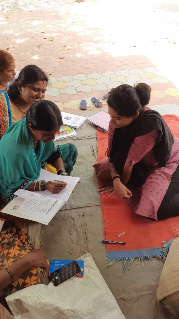 Savine Ventures with a woman in a rural community, helping her fill out documents during a CSR outreach program.